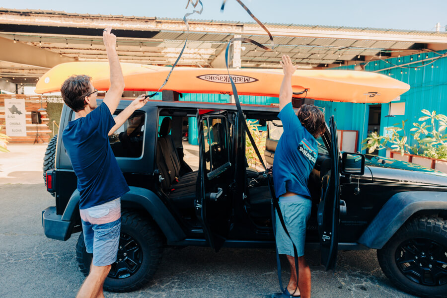 Active Oahu staff throw straps over vehicle and kayak