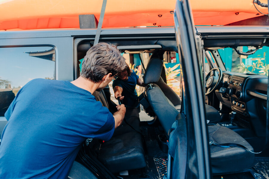 One staff member passes the strap through the vehicle to another staff member