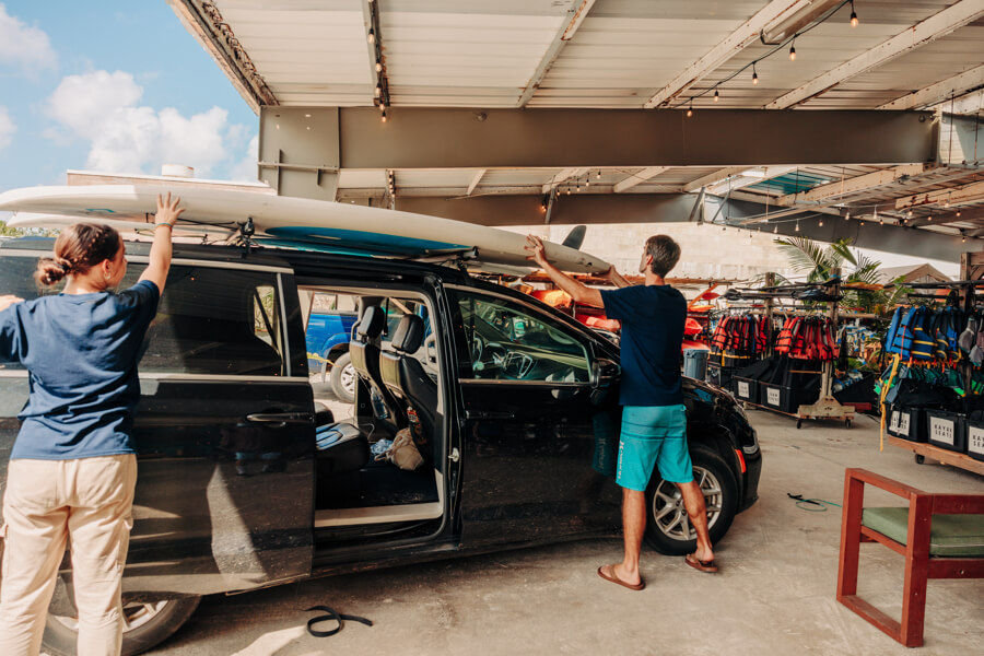 Active Oahu staff place a paddle board on top of a vehicle