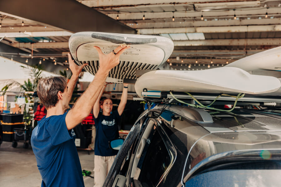 Active Oahu staff lift another paddle board onto a vehicle