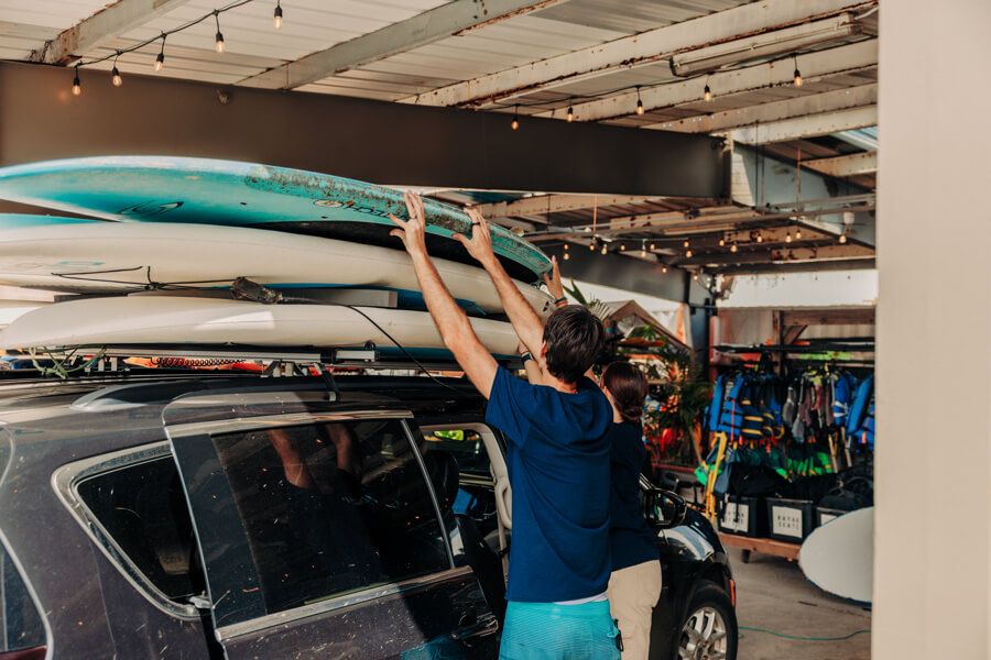 Active Oahu staff stack three paddleboards on top of a vehicle