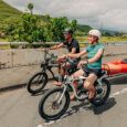 a man tows a kayak with an e-bike equipped with a trailer and a girl rides an e-bike