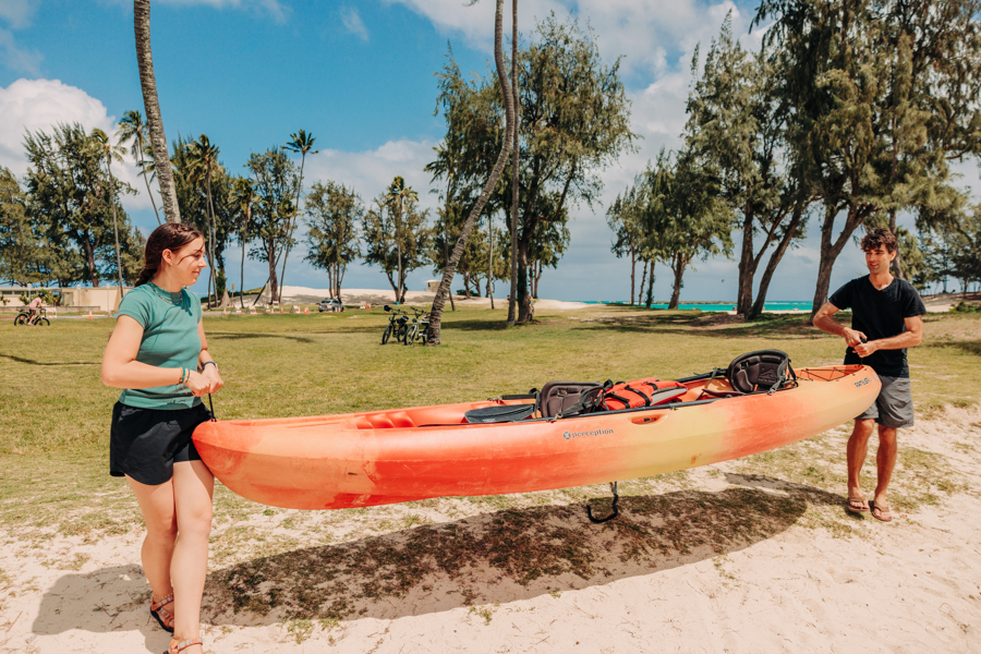 two people carry a kayak to the launch spot of Kailua Beach