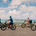 four guests ride e-bike rentals on a path overlooking the ocean