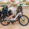 A guy locks up his e-bike and beach gear on a bike rack.