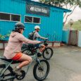 two guests ride e-bikes in front of the Active Oahu shop