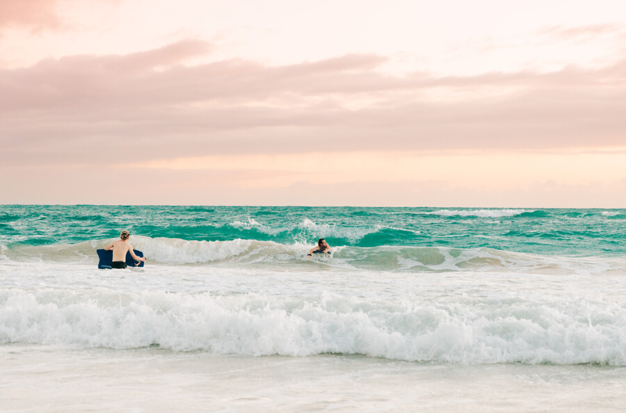 two people catching waves with their boogie board rentals from Active Oahu