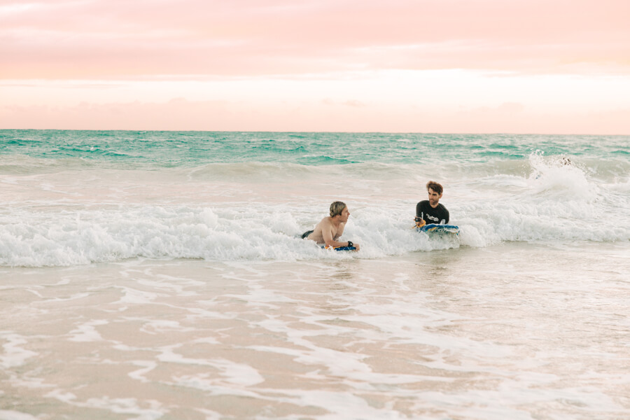 Two people catching a wave at Kalama Beach with their boogie board rentals from Active Oahu
