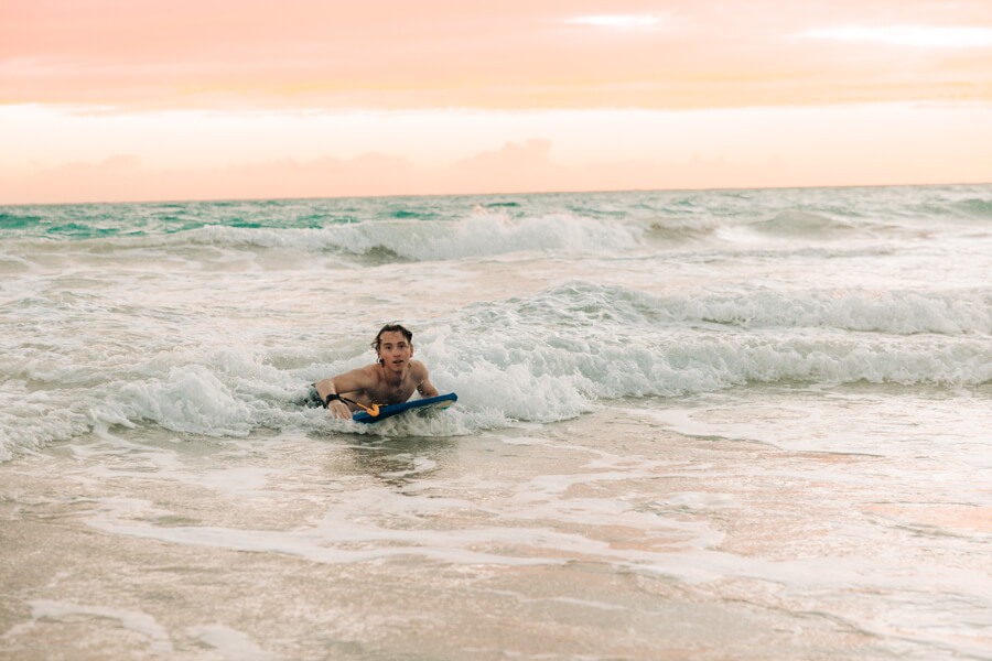 A boy rides a wave on a boogie board rental from Active Oahu