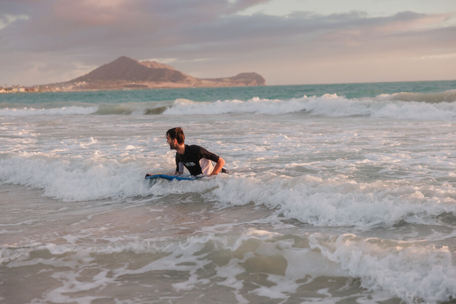 a person catches a wave into shore at Kalama Beach with their boogie board rental from Active Oahu