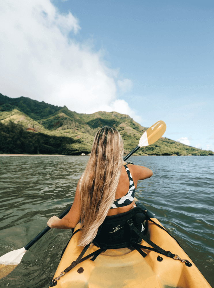 A girl paddling a tandem kayak rental from Active Oahu in Kahana Bay