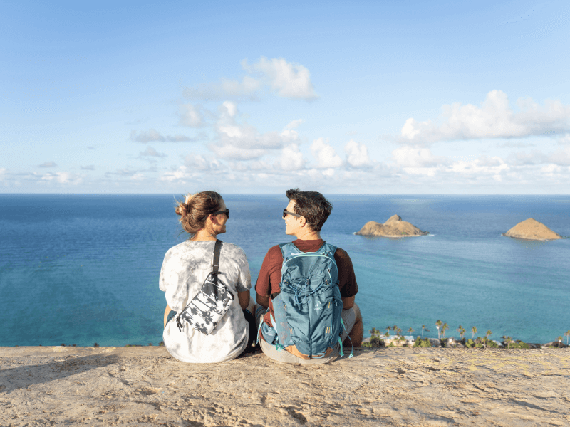 Two people sit on top of the Lanikai Pillbox overlooking the ocean