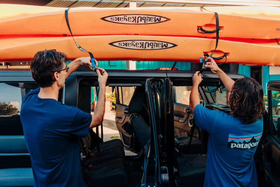 Two tandem kayaks from Active Oahu secured on top of a jeep