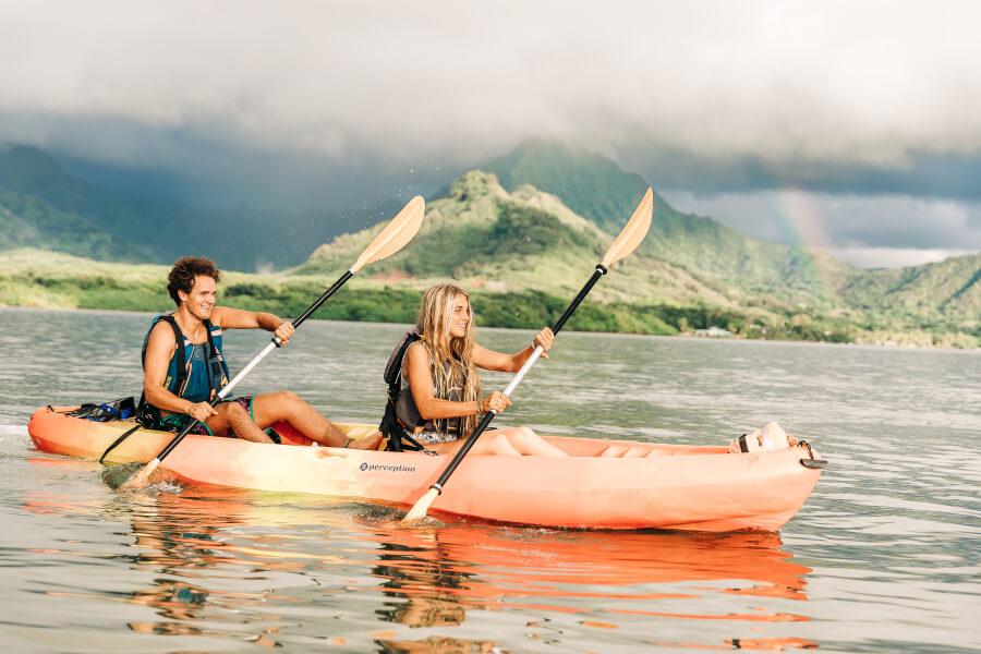 A man and a woman kayak in the ocean