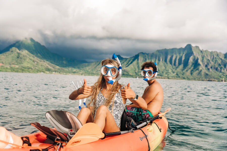 Two people wearing snorkel gear from Active Oahu sitting in a tandem kayak rental.