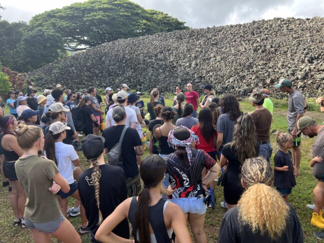 a group of volunteers gathered in front of an ancient Hawaiian temple